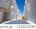 An impressive Carrara marble quarry showcases its massive scale, with a machine for extraction creating a stark contrast to the beautiful blue sky above 132022696