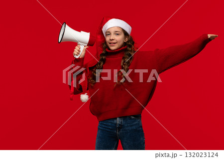 Smiling girl in Santa hat and red sweater holds megaphone 132023124