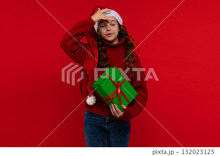 Young girl in Santa hat holds green gift box 132023125