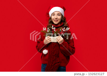 Smiling girl in Santa hat holds Christmas stocking filled Smiling girl in Santa hat holds Christmas stocking filled 132023127