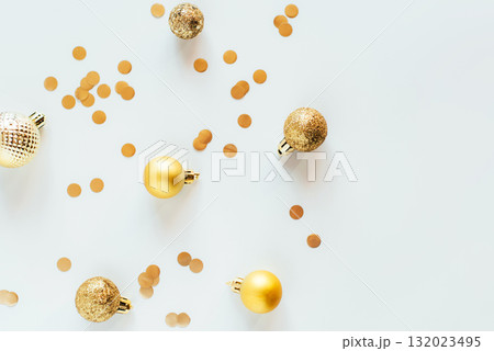 Golden Christmas balls and confetti on a white table in bright light 132023495