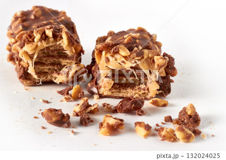 Two pieces of wafer-caramel bar sprinkled with nuts and covered in chocolate 132024025