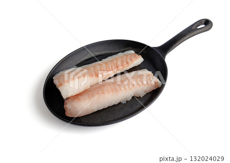 Two pieces of fish fillet on a black cast iron frying pan isolated on white background Two pieces of fish fillet on a black cast iron frying pan isolated on white background 132024029