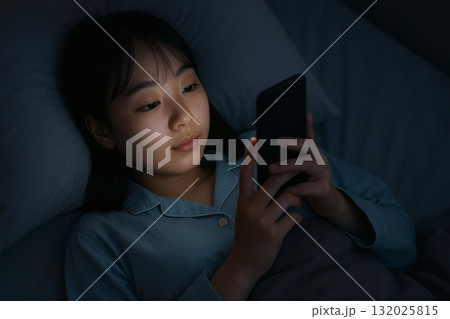 眠る前にベッドでスマートフォンを見ている人 132025815