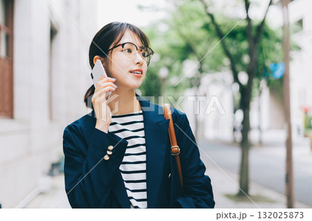 電話をしながら街を歩く若い女性 132025873