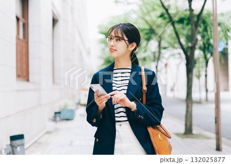 スマホを見ながらお店を探す若い女性 スマホを見ながらお店を探す若い女性 132025877