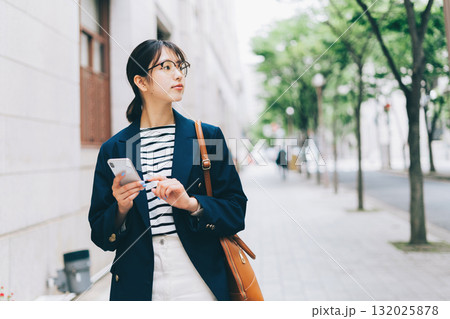 スマホを見ながらお店を探す若い女性 スマホを見ながらお店を探す若い女性 132025878