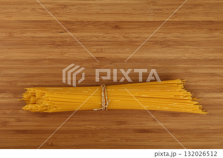 Bunch of raw spaghetti tied with string on wooden table 132026512