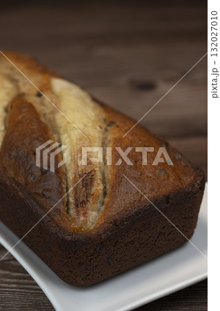Freshly baked banana bread with golden crust served on a plate 132027010