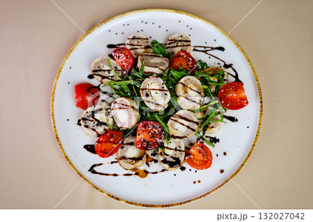 Step by step salad preparation with sliced chicken and liver rolls on a bed of arugula topped with tomato slices black and white sesame and a drizzle of olive oil in a bright kitchen Step by step salad preparation with sliced chicken and liver rolls on a bed of arugula topped with tomato slices black and white sesame and a drizzle of olive oil in a bright kitchen 132027042