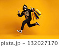 Happy man in skeleton grim reaper costume running and holding shopping bags, celebrating Halloween 132027170