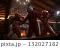 Friends wearing scary costumes dancing in halloween party in a wooden house 132027182
