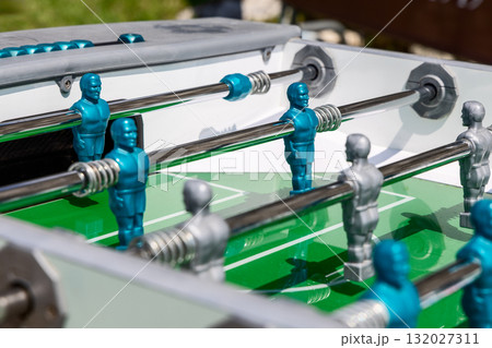 Close view of foosball table with blue and silver players shining under summer sunlight 132027311