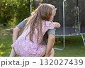 Senior grandfather riding happy smiling granddaughter on back in garden 132027439