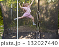 Child girl jumping on trampoline outdoors in the yard on summer vacation. 132027440