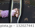 Happy excited child girl lying on trampoline outdoor showing thumb up sign 132027441
