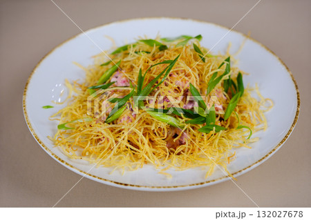 salad with dry fried potatoes Bowl of crispy vegetable salad topped with golden chips and fresh greens, served on a marble table, accompanied by bread and other dishes in the background. 132027678