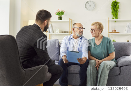 Senior couple with advisor at home reviewing financial documents, planning 132029498