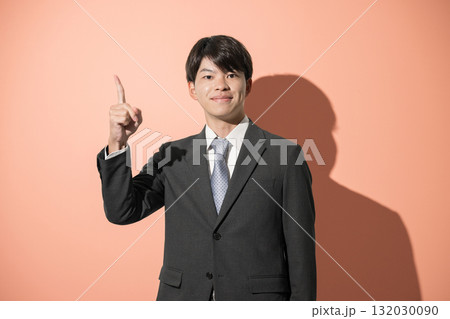 指差しをするスーツを着た若い新卒のようなビジネスマンのカメラ目線 就活などのイメージ オレンジ背景 指差しをするスーツを着た若い新卒のようなビジネスマンのカメラ目線 就活などのイメージ オレンジ背景 132030090