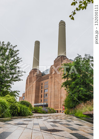 Battersea Power Station chimneys, London heritage landmark amid lush plants 132030111