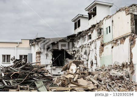 Demolition of a building in progress with debris scattered at the site in a cloudy environment Demolition of a building in progress with debris scattered at the site in a cloudy environment 132030194