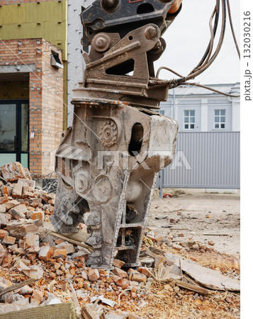 Excavator dismantles building as debris scatter across construction site in urban area 132030216