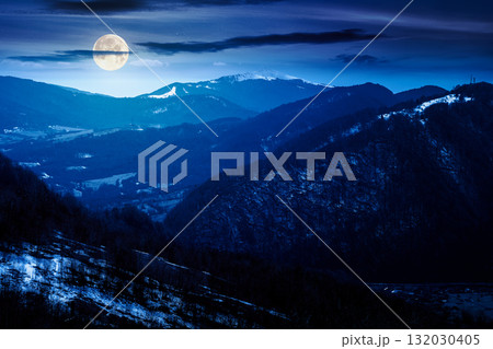 mountainous countryside at night. winter to spring season change scenery. melting snow and leafless trees on the rolling hills in full moon light. view to the distant valley mountainous countryside at night. winter to spring season change scenery. melting snow and leafless trees on the rolling hills in full moon light. view to the distant valley 132030405