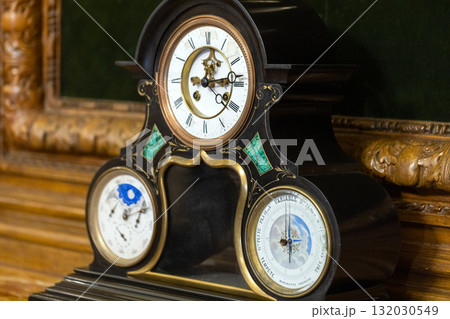 Luxurious Victorian mantel clock featuring a black case, gold trim, and moon phases 132030549
