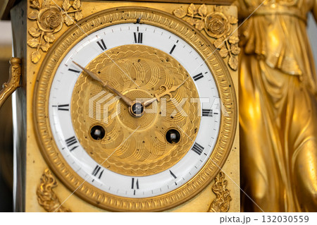 Luxurious gold clock featuring etched dial and Roman numerals, close up photo 132030559