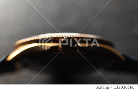 A dramatic close-up of a bronze-toned watch crown, highlighting the textured bezel 132030560