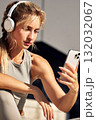 Woman wearing headphones takes a selfie with her phone during an outdoor workout session 132032067