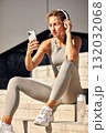 Athletic woman with headphones checking her phone on outdoor steps, ready for a workout 132032068