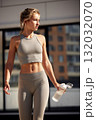 Athletic woman in neutral gym wear outdoors holding water bottle in an urban setting 132032070