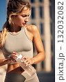 Healthy fitness model wearing beige sportswear outdoors, holding a water bottle during workout 132032082