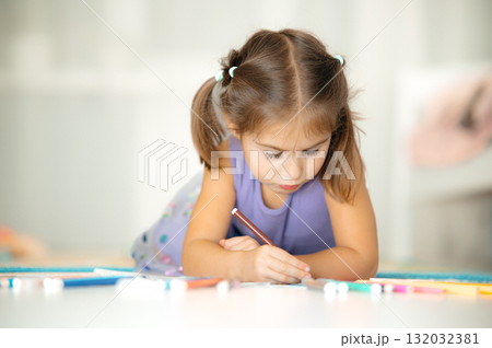 Young girl drawing at a table focused child creating colorful artwork during playtime Young girl drawing at a table focused child creating colorful artwork during playtime 132032381