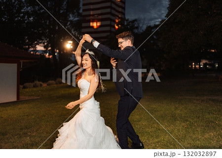 Happy interracial wedding couple dancing during outdoor reception 132032897