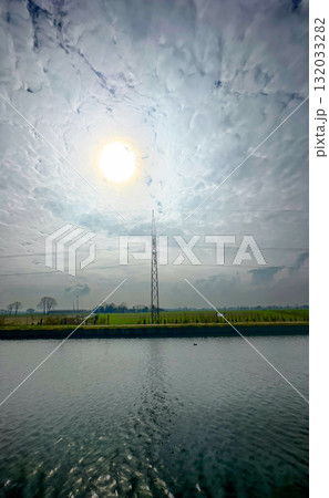 A Beautiful and Serene Landscape Featuring a Communication Tower and Reflective Water 132033282