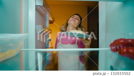 Pregnant female craving dessert at night in the fridge. Pregnant female craving dessert at night in the fridge. 132033502