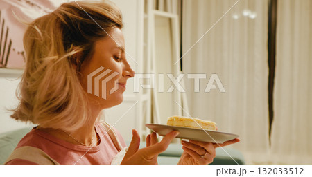 Happy pregnant woman smells sweet cake in anticipation of eating it. Happy pregnant woman smells sweet cake in anticipation of eating it. 132033512