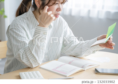通帳を眺める女性 132033902