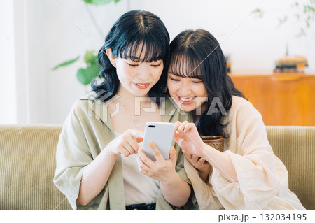 部屋でスマホを見る笑顔の女性2人組 132034195