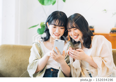 部屋でスマホを見る笑顔の女性2人組 132034196