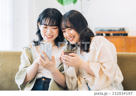 部屋でスマホを見る笑顔の女性2人組 132034197