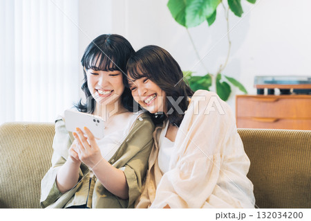 部屋でスマホを見る笑顔の女性2人組 132034200