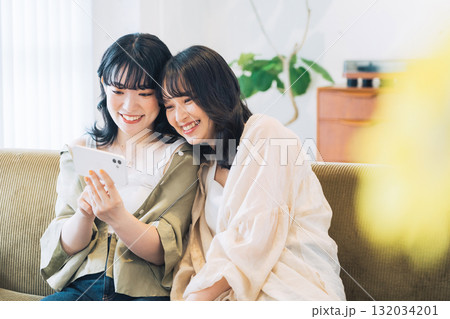 部屋でスマホを見る笑顔の女性2人組 132034201