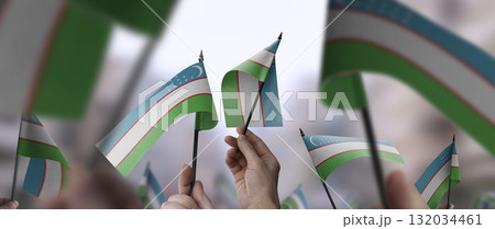Uzbekistan flags in their hands on a blurred urban background Uzbekistan flags in their hands on a blurred urban background 132034461