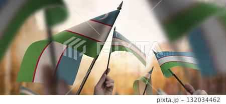 Uzbekistan flags in their hands on a blurred urban background Uzbekistan flags in their hands on a blurred urban background 132034462