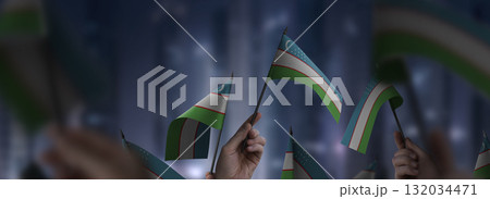 Uzbekistan flags in their hands on a blurred urban background 132034471