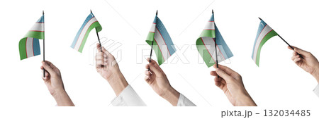 The Uzbekistan flag in hand in different angles on a white background The Uzbekistan flag in hand in different angles on a white background 132034485
