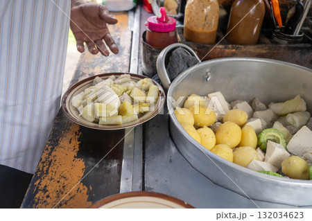 Traditional Indonesian street food vendor preparing Siomay, a popular steamed fish dumpling dish, for a customer. 132034623